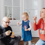 Family enjoying quality time blowing bubbles indoors, capturing joyful moments.